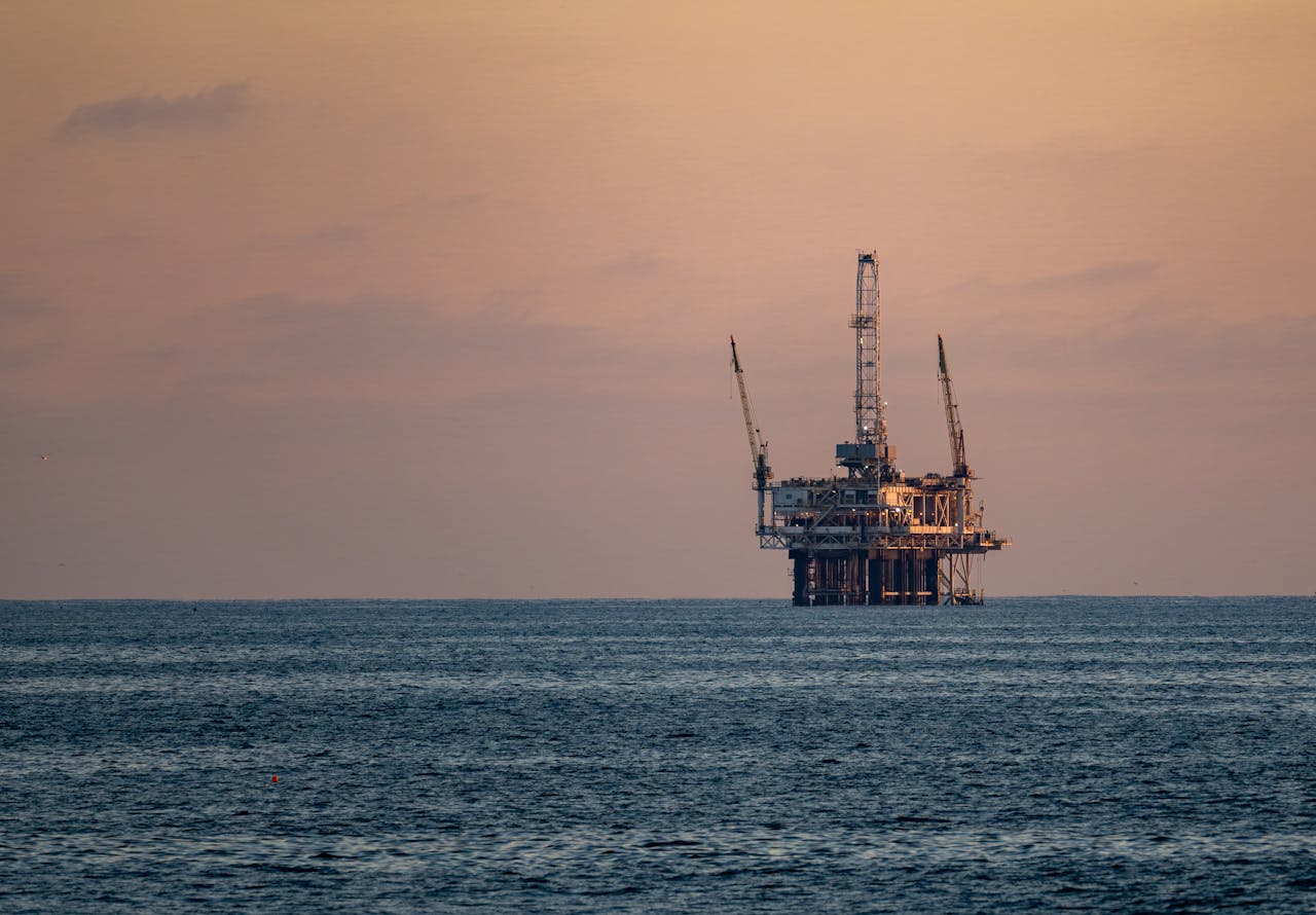Industrial complex with tall smokestacks against a sunset sky.
